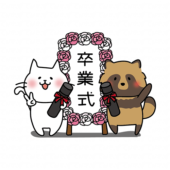 卒業式の看板の前で写真を撮る白い猫とタヌキ